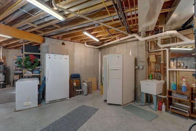 unfinished below grade area with water heater, white refrigerator with ice dispenser, freestanding refrigerator, and a sink