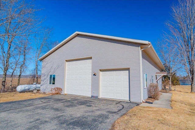 view of side of home featuring a garage and aphalt driveway