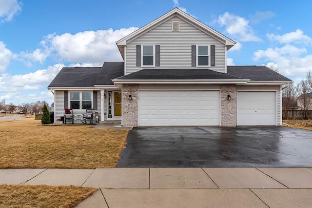 traditional-style house featuring driveway, a front lawn, and brick siding