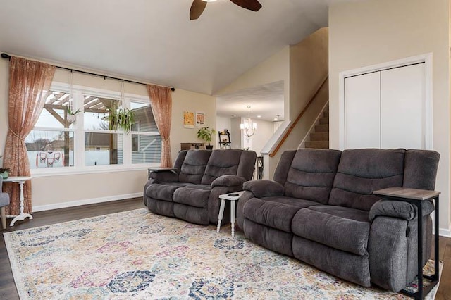 living area featuring stairway, vaulted ceiling, wood finished floors, baseboards, and ceiling fan with notable chandelier