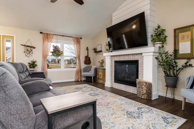 living room featuring lofted ceiling, a fireplace, dark wood finished floors, and baseboards