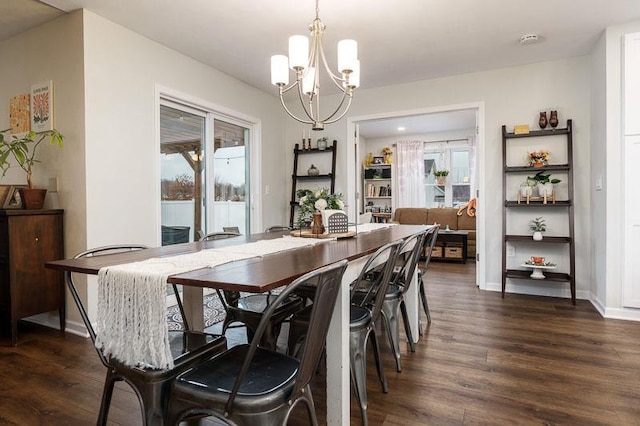 dining area with dark wood-style floors, plenty of natural light, a chandelier, and baseboards