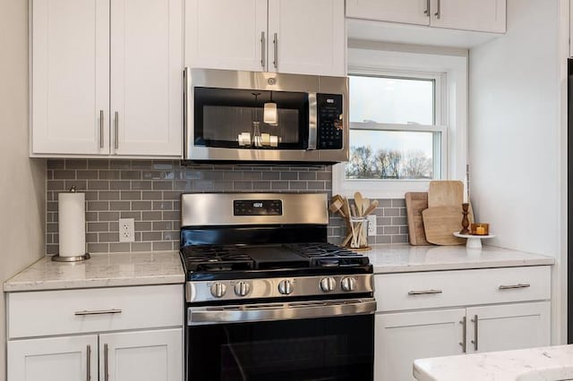 kitchen with appliances with stainless steel finishes, decorative backsplash, light stone counters, and white cabinets