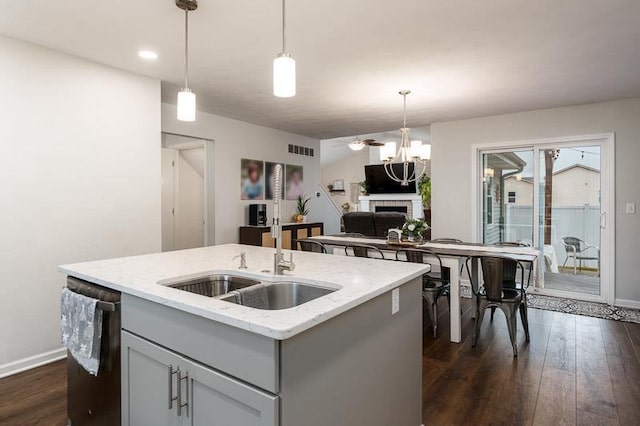 kitchen featuring visible vents, dishwasher, gray cabinetry, a fireplace, and a sink