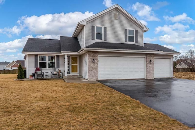 traditional-style home with aphalt driveway, brick siding, an attached garage, and a front lawn