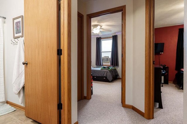 hallway with baseboards and light colored carpet