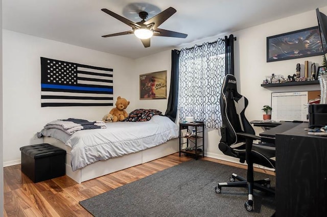 bedroom with a ceiling fan, baseboards, and wood finished floors