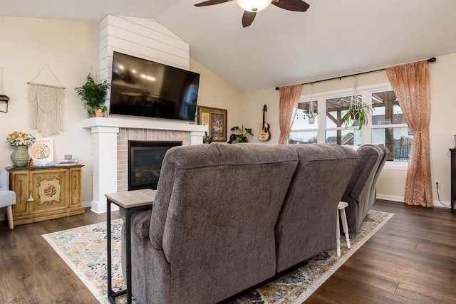 living area with dark wood finished floors, a fireplace, vaulted ceiling, ceiling fan, and baseboards