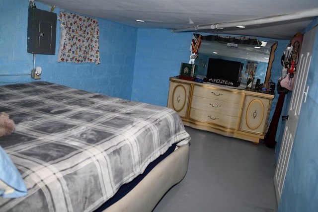 bedroom with concrete block wall, electric panel, and concrete floors