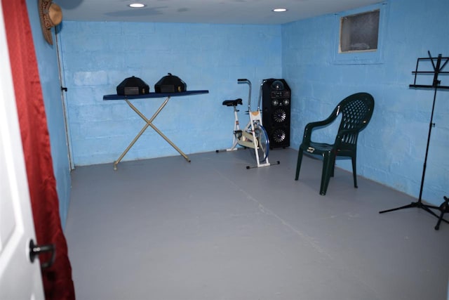 living area featuring recessed lighting, concrete block wall, and finished concrete floors