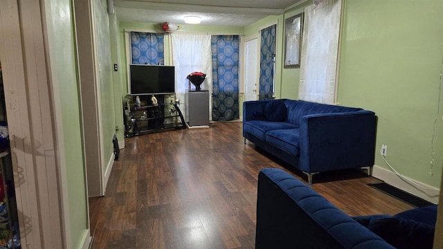 living area with a textured ceiling, baseboards, and wood finished floors