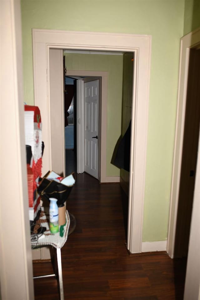 hall featuring dark wood-type flooring and baseboards