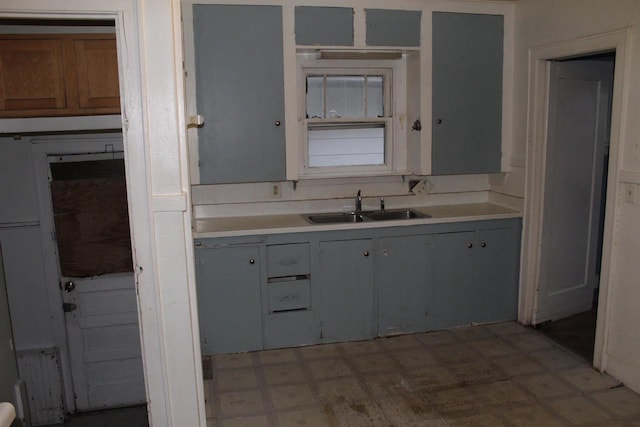 kitchen with light floors, gray cabinets, light countertops, and a sink