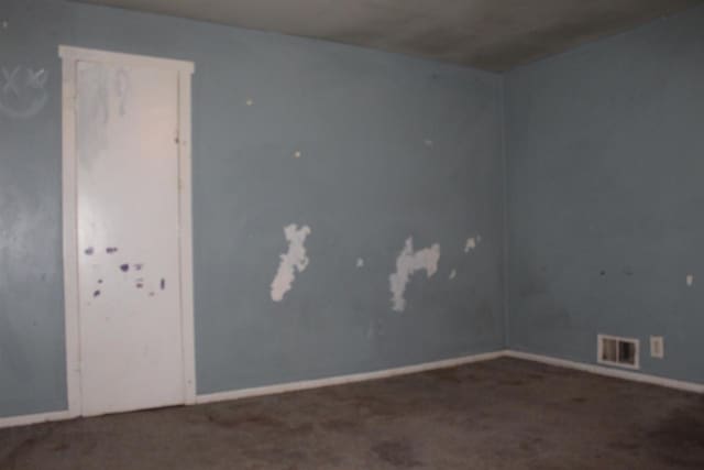 spare room featuring carpet, visible vents, and baseboards