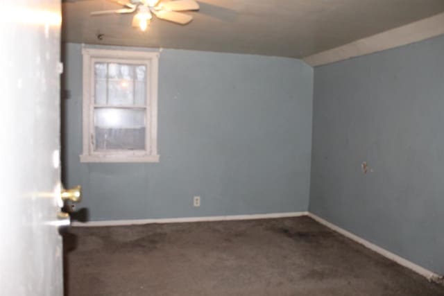 carpeted empty room with lofted ceiling, a ceiling fan, and baseboards