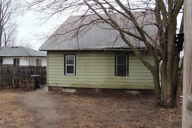 back of property with crawl space, roof with shingles, and fence