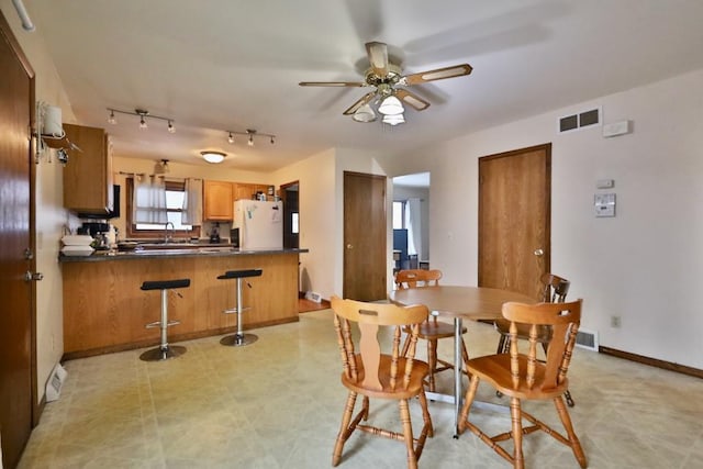 dining space with light floors, baseboards, visible vents, and a ceiling fan