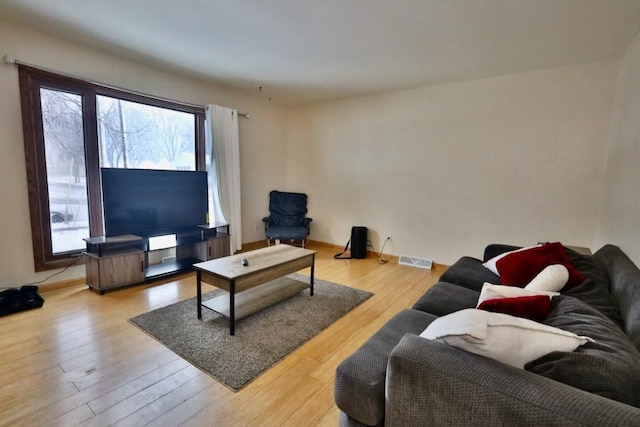 living room featuring light wood-type flooring, visible vents, and baseboards