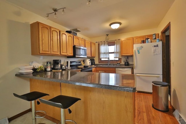 kitchen with a peninsula, dark countertops, visible vents, and appliances with stainless steel finishes