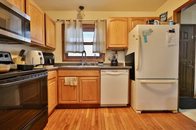 kitchen featuring dark countertops, white appliances, light wood-style flooring, and a sink