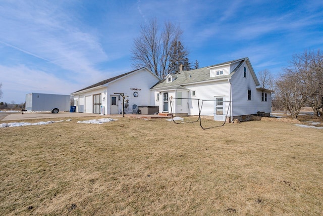 rear view of property with a garage, a chimney, and a yard