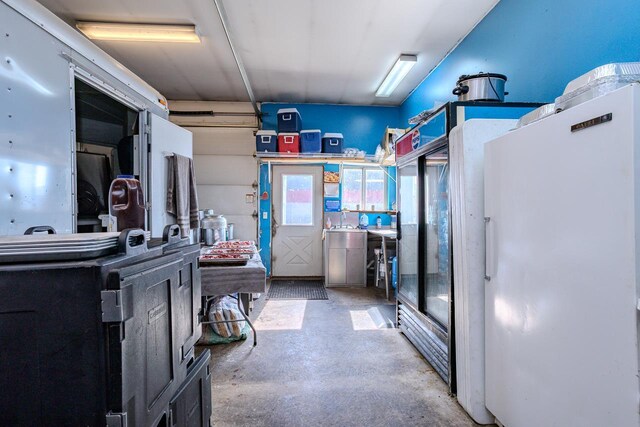 kitchen with unfinished concrete flooring and freestanding refrigerator