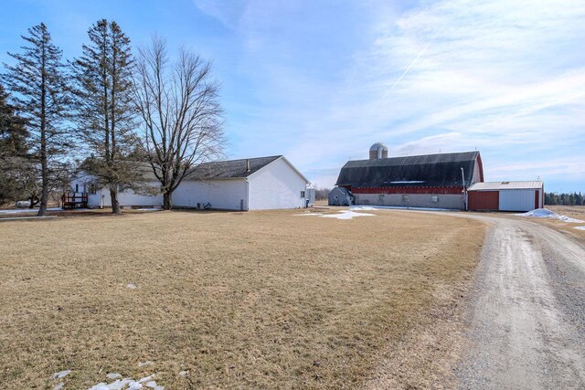 view of home's exterior featuring an outbuilding, a yard, and dirt driveway