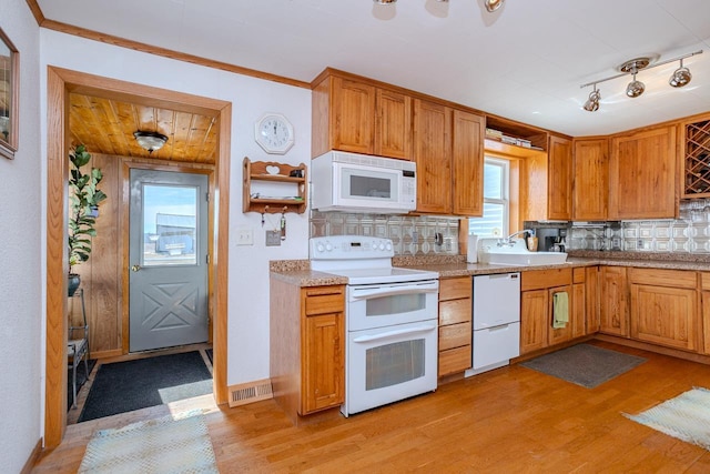 kitchen featuring white appliances, a sink, light countertops, decorative backsplash, and light wood finished floors