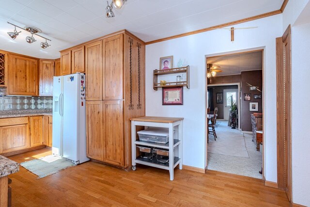 kitchen featuring light wood-style floors, white fridge with ice dispenser, decorative backsplash, and light countertops