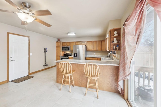 kitchen featuring stainless steel appliances, a peninsula, a sink, light countertops, and a wealth of natural light