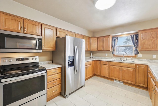 kitchen featuring stainless steel appliances, light countertops, visible vents, and a sink