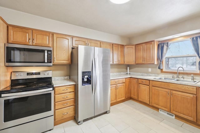 kitchen featuring stainless steel appliances, light countertops, visible vents, and a sink