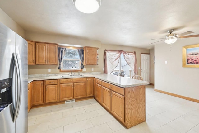 kitchen with a peninsula, a sink, visible vents, light countertops, and stainless steel refrigerator with ice dispenser