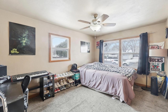 carpeted bedroom with a ceiling fan, multiple windows, and baseboards