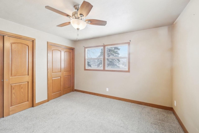 unfurnished bedroom featuring light carpet, a ceiling fan, and baseboards