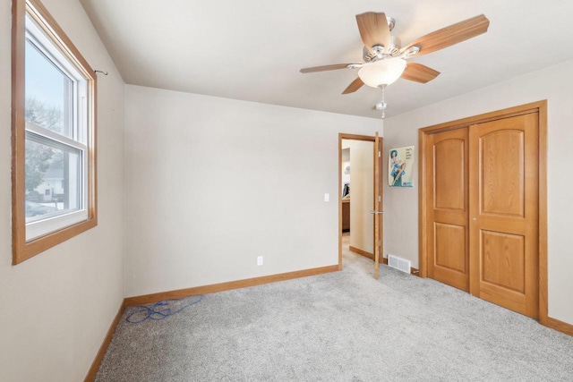 unfurnished bedroom featuring carpet, a closet, visible vents, a ceiling fan, and baseboards