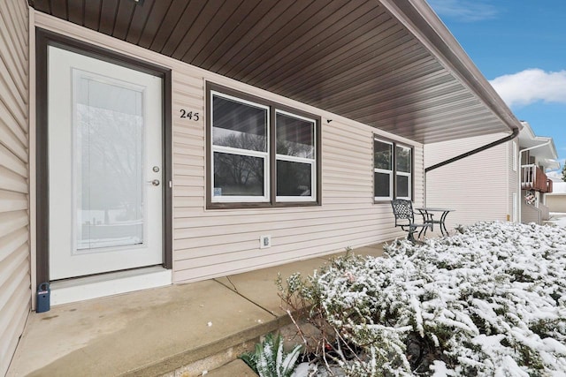 snow covered property entrance with a porch