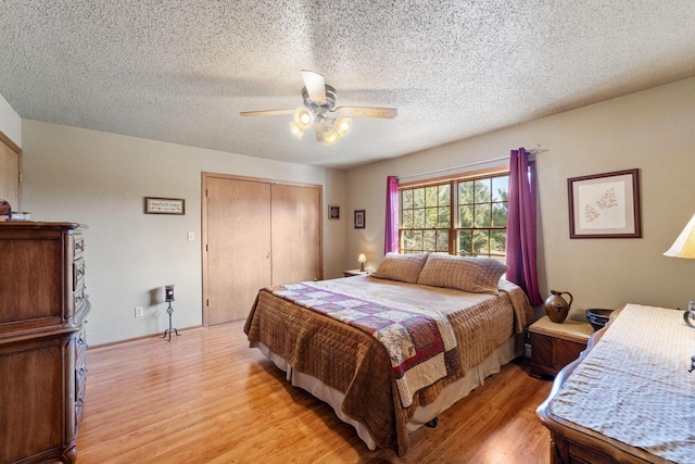 bedroom featuring a textured ceiling, light wood finished floors, a closet, and a ceiling fan