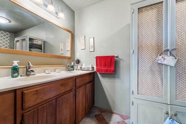 bathroom featuring double vanity, baseboards, tile patterned floors, a textured ceiling, and a sink