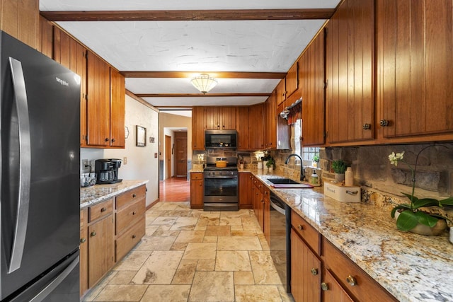 kitchen featuring decorative backsplash, brown cabinetry, appliances with stainless steel finishes, stone tile flooring, and a sink