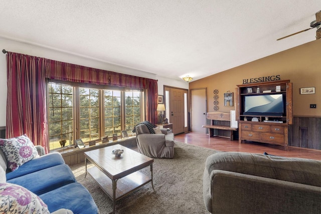 living area with wainscoting, vaulted ceiling, a textured ceiling, and wood finished floors