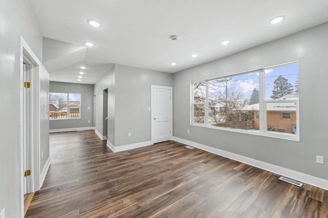 empty room featuring dark wood-style floors, baseboards, visible vents, and recessed lighting