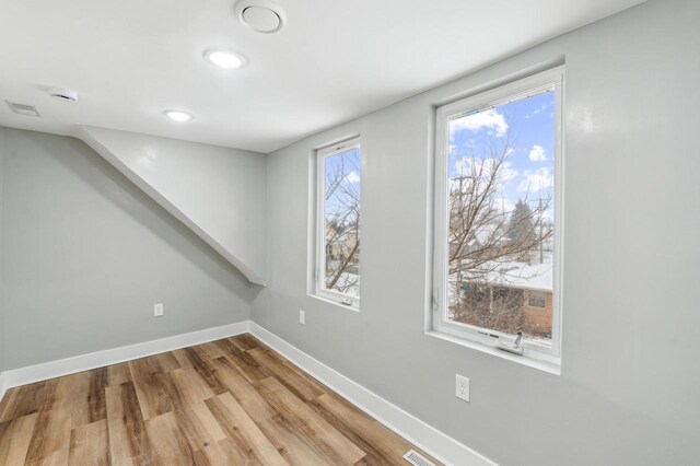 basement with visible vents, baseboards, and wood finished floors