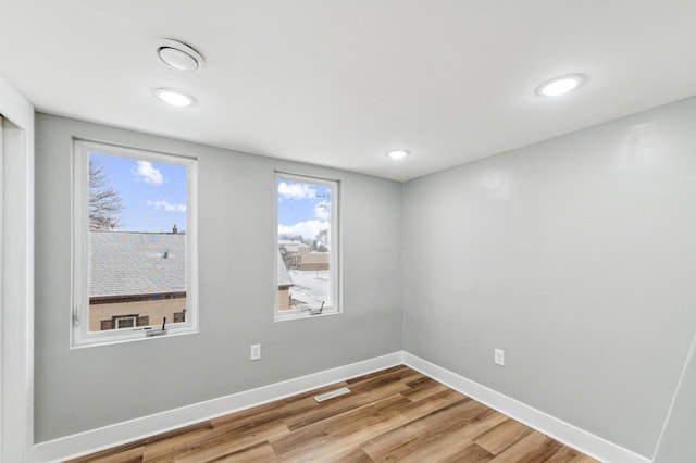 spare room with light wood-style flooring, visible vents, and baseboards