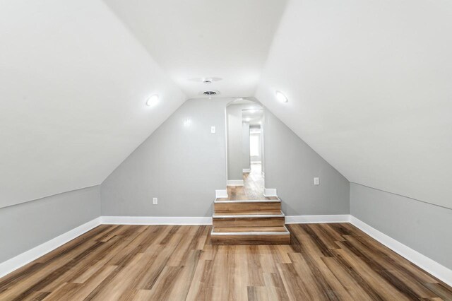 bonus room with lofted ceiling, baseboards, and wood finished floors
