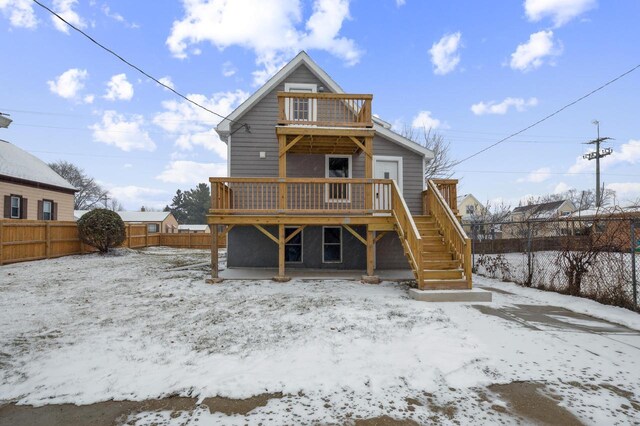 snow covered rear of property featuring a deck, stairway, and a fenced backyard