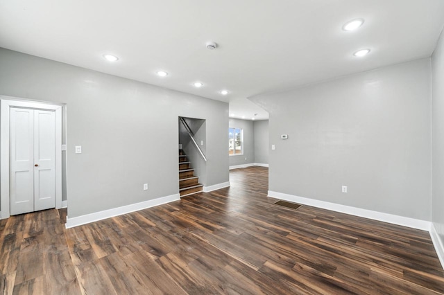 empty room featuring dark wood-style floors, recessed lighting, visible vents, and stairway