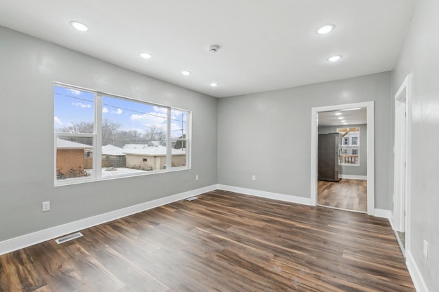 spare room with recessed lighting, visible vents, dark wood finished floors, and baseboards