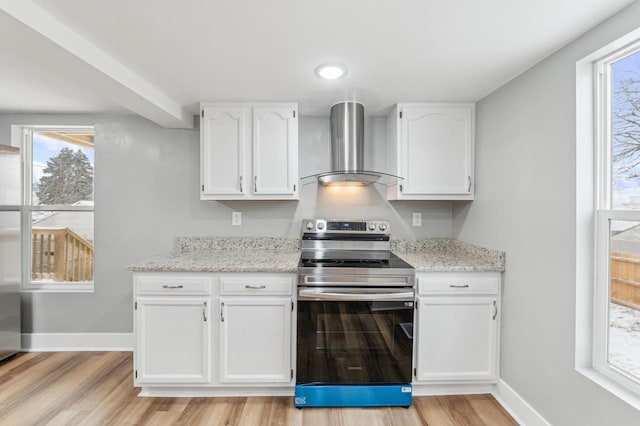 kitchen featuring wall chimney range hood, light wood-style flooring, stainless steel electric stove, and white cabinets