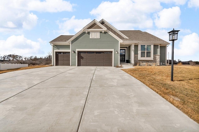 craftsman-style home featuring an attached garage, driveway, a front lawn, and roof with shingles